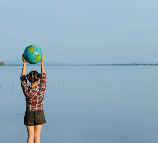 Photo of a young girl holding a globe above her head